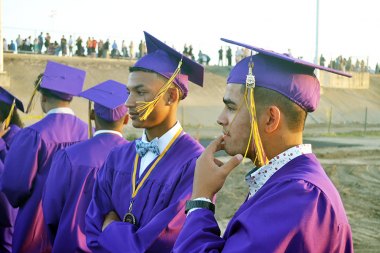 
A pair of Lemoore High grads ponder the upcoming ceremony in Tiger Stadium.
